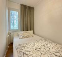 2-izbový byt 45m2 | Sklenárová - Ružinov - Spálňa v 2-izbovom byte s posteľou, oknom a závesmi, podlaha s dreveným dekorom.