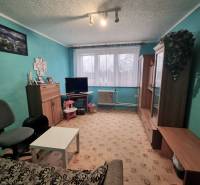 Predaj 3 - izbového bytu v Kuklove !!! - Obývacia izba v 3-izbovom byte s tyrkysovými stenami, nábytkom a kobercovou podlahou.