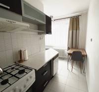 Ponuka na prenájom 2,5 izbový byt Zl. Potok - Kuchyňa v 2-izbovom byte so sporákom, tmavým nábytkom a svetlou dlažbou.