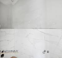 Na predaj 4-izbové novostavby, Veľká Paka - Kúpeľňa v rodinnom dome s bielymi mramorovými obkladmi bez zariaďovacích predmetov.