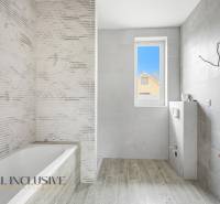 Na predaj 4-izbové novostavby, Veľká Paka - Kúpeľňa v rodinnom dome s vaňou, sivými obkladmi a podlahou s dreveným dekorom.