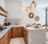 LUXUSNÁ 3-SPÁLŇOVÁ VILA S BAZÉNOM – CANGGU, BALI - Interiér vily s kuchynským kútom, drevenými skrinkami a dekoratívnymi zrkadlami.