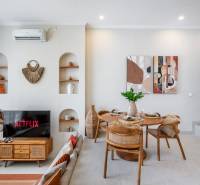 LUXUSNÁ 3-SPÁLŇOVÁ VILA S BAZÉNOM – CANGGU, BALI - Obývačka vily s TV, jedálenským stolom a dekoračnými prvkami na stenách.