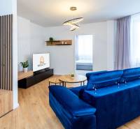 PRENÁJOM | 3i byt v centre Prešova | ZARIADENÝ - Obývačka v 3-izbovom byte s modrou pohovkou a podlahou s dreveným dekorom.