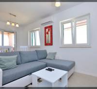 PRIVLAKA - BYT S4- dvojizbový byt 63,42 m2 vzdialený 150 m od mora - Obývačka s šedou pohovkou, konferenčný stolík a jedálenský stôl v 2-izbovom byte.