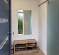 Moderný 3-izbový byt so záhradou Šamorín-Kráľovianky - 3-izbový byt s lavicou na topánky, zrkadlom a podlahou s dreveným dekorom.