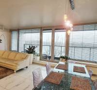 Luxusný 3-izb. byt s famóznym výhľadom na Dunaj, River Park - Obývačka v 3-izbovom byte so svetlou sedačkou, stolom a presklenými dverami.