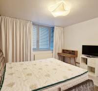 Luxusný 3-izb. byt s famóznym výhľadom na Dunaj, River Park - Spálňa v 3-izbovom byte s posteľou, televízorom a písacím stolom.