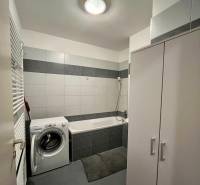 Prenájom 2-izb bytu Dlhé diely - Kúpeľňa s práčkou, vaňou a bielou dlažbou v 2-izbovom byte.