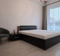 PREDAJ - 3 izbový byt blízko centra - Pivovarská ulica Nitra - Spálňa v 3-izbovom byte s posteľou, kreslom a podlahou s dreveným dekorom.