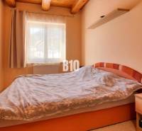 Praktický 8-izbový rodinný dom na Bystričke: Vhodný pre veľkú rodinu z - Spálňa v rodinnom dome s televízorom, posteľou a drevenými stropnými trámami.