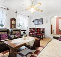 REZERVOVANÉ 4-izb. rodinný dom s garážou, Čierny Brod - Obývacia izba Rodinného domu s kozubom, čiernymi sedačkami a podlahou s dreveným dekorom.