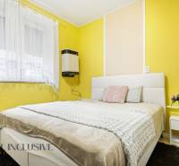 REZERVOVANÉ 4-izb. rodinný dom s garážou, Čierny Brod - Spálňa v Rodinnom dome so žltými stenami, bielou posteľou a kvetinovou dekoráciou.