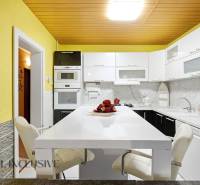 REZERVOVANÉ 4-izb. rodinný dom s garážou, Čierny Brod - Kuchyňa s bielym pultom, žltými stenami a modernými spotrebičmi v rodinnom dome.
