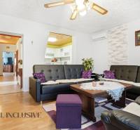 REZERVOVANÉ 4-izb. rodinný dom s garážou, Čierny Brod - Obývacia izba v rodinnom dome s podlahou s dreveným dekorom a čiernymi koženými sedačkami.