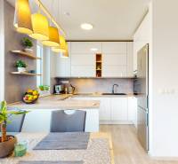 BA/PETRŽALKA-Prenájom moderného 3i bytu s parkovacím státim-Slnečnice - Kuchyňa v 3-izbovom byte s podlahou s dreveným dekorom, svietidlami a izbovými rastlinami.