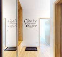 BA/PETRŽALKA-Prenájom moderného 3i bytu s parkovacím státim-Slnečnice - Vstupná chodba s podlahou s dreveným dekorom v 3-izbovom byte a nápisom na stene.