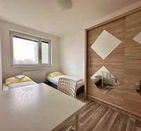 | PREDAJ | 3 izbový byt s veľkou loggiou – Banšelova, Ružinov - Spálňa s dvomi posteľami, bielym stolom a skriňou v 3-izbovom byte.