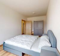 | 3-izbový byt v novostavbe, ul. Odevná + parking | Trenčín  - Spálňa v 3-izbovom byte s posteľou, šatníkom a podlahou s dreveným dekorom.