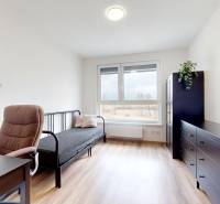 | 3-izbový byt v novostavbe, ul. Odevná + parking | Trenčín  - Izba s podlahou s dreveným dekorom, pracovným stolom a pohovkou v 3-izbovom byte.