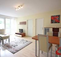 **BEZ PROVÍZIE**3-IZBOVÝ BYT S BALKÓNOM A LOGGIOU NA PALISÁDACH**      - Obývacia izba v 3-izbovom byte s podlahou s dreveným dekorom, sedačkou a jedálenským stolom.