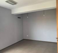 Predaj modernej administratívnej budovy v Bratislave, okres II - Prázdna izba s bielymi stenami a drevenými dverami. Nepoužívaná budova.