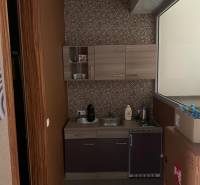 Predaj modernej administratívnej budovy v Bratislave, okres II - Malá kuchynka s mozaikovým obkladom, umývadlom, skrinkami a spotrebičmi v budove.