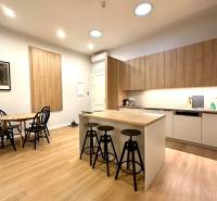 Prenájom priestranného 2-izbového bytu v absolútnom centre Košíc - Kuchyňa v 2-izbovom byte s ostrovčekom, stoličkami a podlahou s dreveným dekorom.