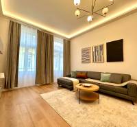 Prenájom priestranného 2-izbového bytu v absolútnom centre Košíc - Obývačka v 2-izbovom byte s podlahou s dreveným dekorom, šedou sedačkou a dekoratívnymi obrazmi.