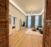 Prenájom priestranného 2-izbového bytu v absolútnom centre Košíc - Obývacia izba v 2-izbovom byte s podlahou s dreveným dekorom a tehličkovou stenou.