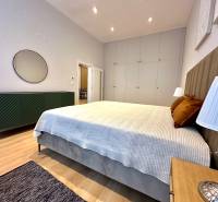 Prenájom priestranného 2-izbového bytu v absolútnom centre Košíc - Spálňa v 2-izbovom byte s posteľou, skriňami a podlahou s dreveným dekorom.