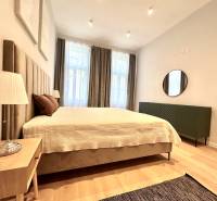 Prenájom priestranného 2-izbového bytu v absolútnom centre Košíc - Spálňa v 2-izbovom byte s veľkou posteľou, lampou a podlahou s dreveným dekorom.