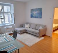 Pekný 2i byt, REKONŠTRUKCIA, CENTRUM, Bukureštská ulica, Staré Mesto - Obývacia izba 2-izbového bytu na ulici Bukurešťská s pohovkou a jedálenským stolom.