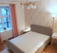 Pekný 2i byt, REKONŠTRUKCIA, CENTRUM, Bukureštská ulica, Staré Mesto - Svetlá spálňa, na ulici Bukurešťská, s posteľou, stolíkom a dekoratívnymi stenami v 2-izbovom byte.