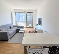 MODERNÝ 3i byt, CUBICON GARDENS, BALKÓN, PARKING, Rudolfa Mocka - Obývačka v 3-izbovom byte s pohodlnou sedačkou a podlahou s dreveným dekorom.