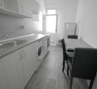 Pekný 3i byt, 3 x NEPRIECH.IZBA, BALKÓN, Radarová ulica, Ostredky - Kuchyňa s jedálenským stolom, skrinkami a podlahou s dreveným dekorom v 3-izbovom byte.