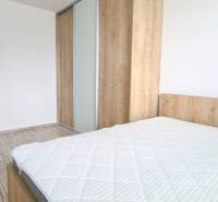 MODERNÝ 2i byt, REKONŠTRUKCIA, KLÍMA, MOZARTOVA ulica, Horský park - Spálňa s posteľou a vstavanou skriňou v 2-izbovom byte, podlaha s dreveným dekorom.