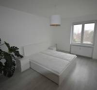 SLNEČNÝ 2i byt, REKONŠTRUKCIA, 2 X SAMOST.IZBA, BALKÓN, Haburská ulica - Spálňa so svetlou podlahou s dreveným dekorom a veľkým oknom v 2-izbovom byte.