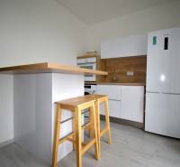 SLNEČNÝ 2i byt, REKONŠTRUKCIA, 2 X SAMOST.IZBA, BALKÓN, Haburská ulica - Kuchyňa v 2-izbovom byte s dreveným dekorom, barovým pultom a stoličkami.