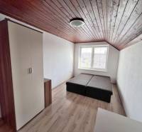 Na prenájom 3i byt v rodinom dome so záhradou - Vojenská ul. Rovinka - Izba so šikmým dreveným stropom, posteľou a skriňou, výhľad smerom na ulicu Vojenská.