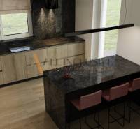 POSLEDNÁ NOVOSTAVBA - HOLODOM | PRÁZNOVCE - Kuchyňa s mramorovým pultom a drevenými skrinkami v rodinnom dome.