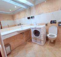 PEKNÁ GARSÓNKA, NOVOSTAVBA, KLÍMA, DRAŽDIAK HAUS, Antolská ulica - Kúpeľňa v garsónke s práčkou, toaletou a umývadlom na svetlých obkladoch.