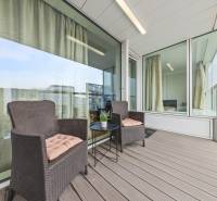 KRÁSNY 2i byt, KLÍMA, LOGGIA,VÝHĽAD,PANORAMA CITY, Landererova ulica - Balkón v 2-izbovom byte s ratanovými kreslami a stolíkom, podlaha s dreveným dekorom.