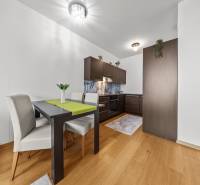 KRÁSNY 2i byt, KLÍMA, LOGGIA,VÝHĽAD,PANORAMA CITY, Landererova ulica - Jedálenský stôl a kuchyňa s tmavým nábytkom, podlaha s dreveným dekorom v 2-izbovom byte.