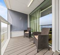 KRÁSNY 2i byt, KLÍMA, LOGGIA,VÝHĽAD,PANORAMA CITY, Landererova ulica - Balkón v 2-izbovom byte s ratanovým nábytkom a výhľadom, podlaha s dreveným dekorom.