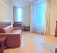 VEĽKOMETRÁŽNY 3i byt, 3 x NEPRIECHODNÁ IZBA, KLÍMA, BALKÓN, Nám.SNP - Izba s gaučom, dreveným nábytkom a podlahou s dreveným dekorom v 3-izbovom byte.