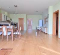 VEĽKOMETRÁŽNY 3i byt, 3 x NEPRIECHODNÁ IZBA, KLÍMA, BALKÓN, Nám.SNP - 3-izbový byt s podlahou s dreveným dekorom, jedálenským stolom a otvorenou kuchyňou.