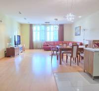 VEĽKOMETRÁŽNY 3i byt, 3 x NEPRIECHODNÁ IZBA, KLÍMA, BALKÓN, Nám.SNP - Obývacia izba v 3-izbovom byte s podlahou s dreveným dekorom, súčasťou je kuchyňa a jedálenský stôl.