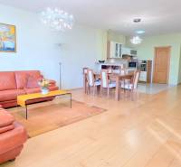 VEĽKOMETRÁŽNY 3i byt, 3 x NEPRIECHODNÁ IZBA, KLÍMA, BALKÓN, Nám.SNP - Obývacia izba s podlahou s dreveným dekorom, kožený gauč, jedálenský stôl, kuchyňa v 3-izbovom byte.