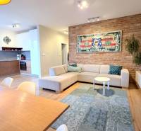 LUXUSNÝ 3i byt, TERASA, PARKING, KLÍMA, ZELENÁ HORKA, Ďumbierska ulica - Obývacia izba v 2-izbovom byte s tehlovou stenou a podlahou s dreveným dekorom.